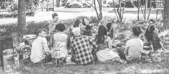 Group of friends making picnic with barbecue on city park outdoor - Young people eating bbq meal and drinking wine - Focus on bottom guys - Black and white editing - Youth concept - Vintage filter