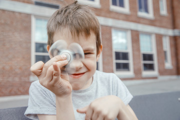 boy turns the fidget spinner and makes faces. child toying with the spinner in the schoolyard
