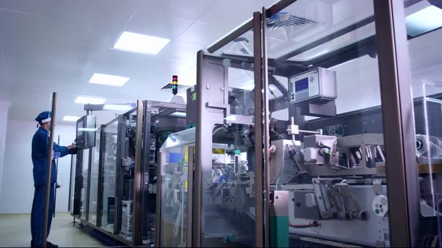 Pharmaceutical industry. Pharmaceutical worker operating pharmacy equipment. Packaging machine at factory. Pharmaceutical manufacturing. Pharmacist control production line. Pharmaceutics industry