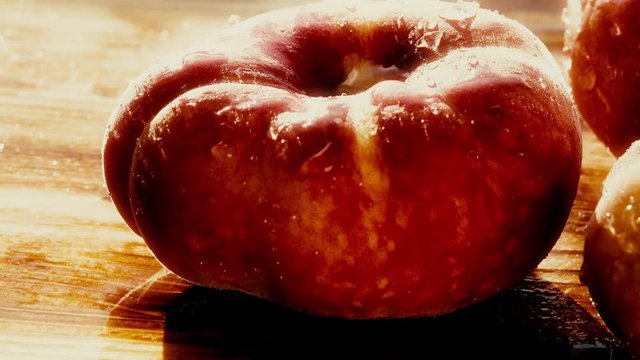 Wet ripe saturn peaches on a wooden table on a sunny day. 4K macro pan shot