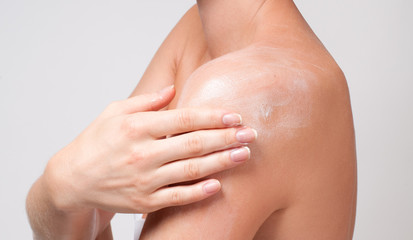 Body care. Woman cares about her shoulder applying cosmetic cream