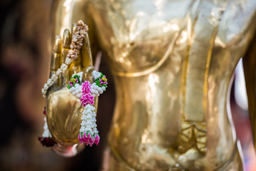 Beautiful garland hang on the Buddha image hand.