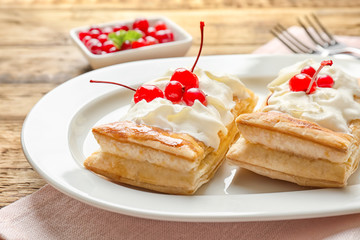 Tasty puff pastry dessert with berries and whipped cream on plate