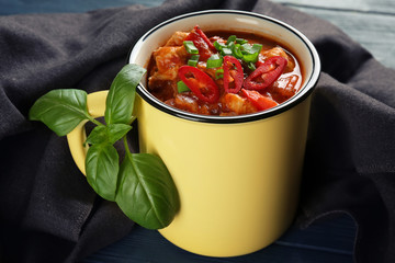 Enamel mug with delicious chili turkey on table, closeup