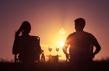 Fototapeta na wymiar Couple relaxing outdoors having a glass on wine while watching the sunset. 