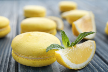 Tasty fresh macaron and lemon slice on wooden table, closeup