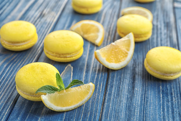 Tasty fresh macarons and lemon slices on wooden table, closeup