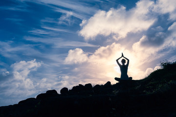 Woman meditating on a mountain top. 