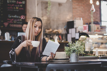 Happy business woman reading book while relaxing at cafe.