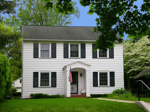 Middle class house with white siding and American flag