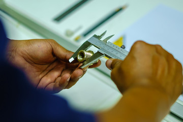 Man's hands using Vernier caliper to measure the object