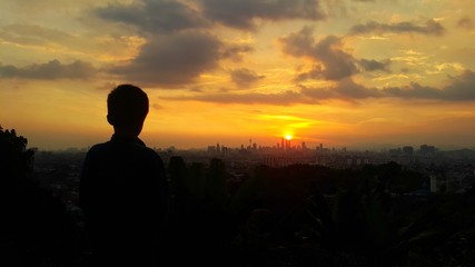 Fototapeta premium Silhouette of young boy during sunset in kuala lumpur city