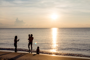 Father, mother, and child Enjoy the sea at dawn.