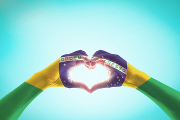 Brazil flag on people hands in heart shape for labor day and national holiday celebration isolated on blue sky background