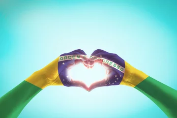 Papier Peint photo Brésil Drapeau du Brésil sur les mains des gens en forme de coeur pour la fête du travail et la célébration de la fête nationale isolée sur fond de ciel bleu