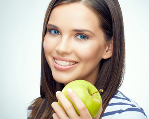 Close up smiling face portrait of young woman with braces on teeth holding green apple.