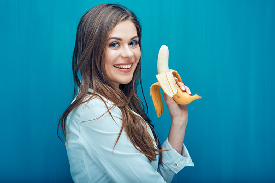 Smiling woman holding banana - source of vitamins and potassium.