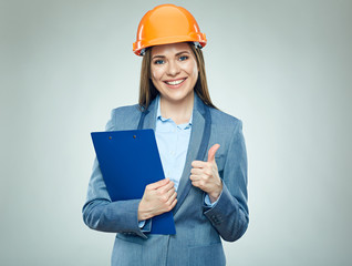 Smiling businesswoman wearing safety helmet holding clipboard