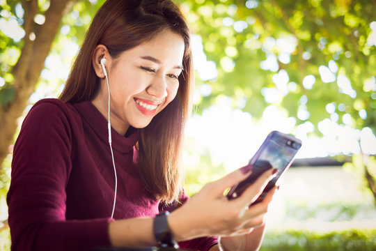 Asian woman Listening Music Media Entertainment by smartphone. Feeling enjoy and happy.