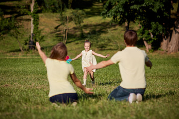 Happy family playing in the park sitting on grass in summer.