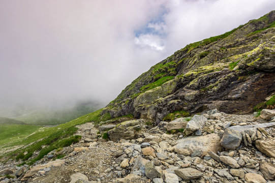 Steep slope on rocky hillside in fog