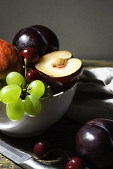 Plums, apples, grapes and cherries on a wooden table.