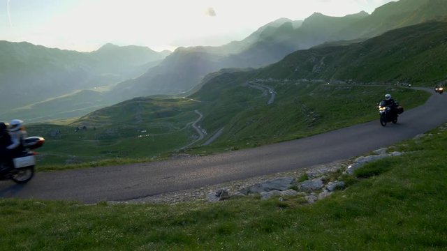 Group of motorcyclists on the mountainous road. Sunset lights.