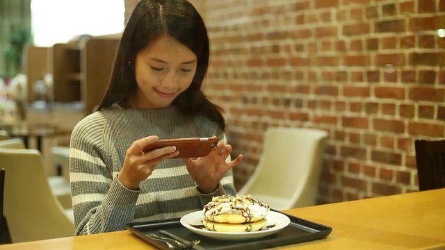 Woman taking photo on her dessert at coffee shop