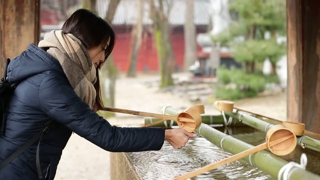 Woman washing with water purification in front of Japanese Temple