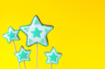 Homemade gingerbreads in the form of turquoise stars on the yellow background. Picture for a menu or a confectionery catalog. Invitation or greeting birthday card. Copy space.