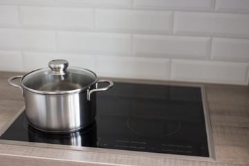 metal pot on electric stove in kitchen - obrazy, fototapety, plakaty