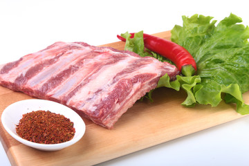 Raw pork ribs with herbs and spices on wooden board. Ready for cooking.