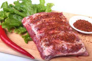 Raw pork ribs with herbs and spices on wooden board. Ready for cooking.