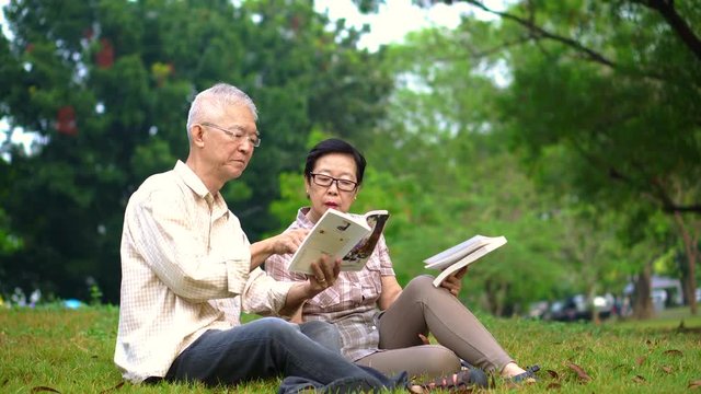 Asian senior couple reading books at the park.Spend quality time and never stop learning something new 4k