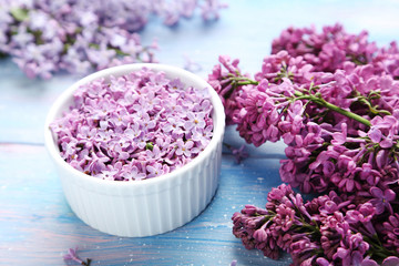 Obraz na płótnie Canvas Lilac flowers in bowl on blue wooden table