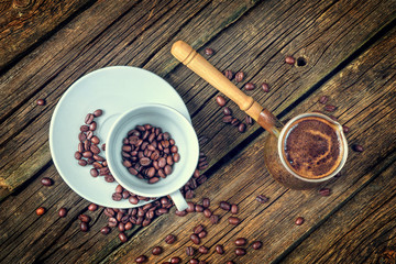 White coffee cup and coffee beans on old wooden background.