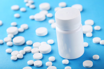 White pills with plastic bottle on blue background