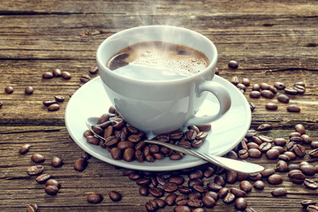 White coffee cup and coffee beans on old wooden background.
