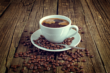 White coffee cup and coffee beans on old wooden background.