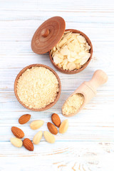 Almonds in bowl and scoop on wooden table