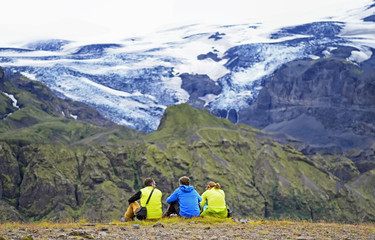 Fototapeta premium Group of hikers sitting on a ledge of a mountain, enjoying the beautiful view valley in Thorsmork, Iceland