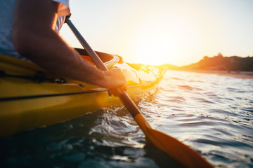 Close up of man holding kayak paddle at sunset