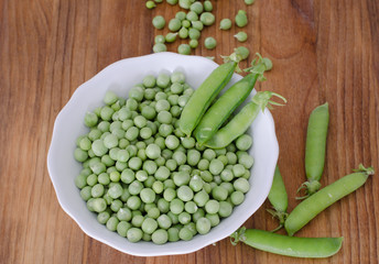 Guisantes en plato sobre fondo de madera