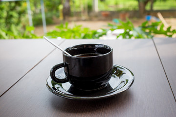 A cup of coffee with leaf pattern in a white cup on wooden background.