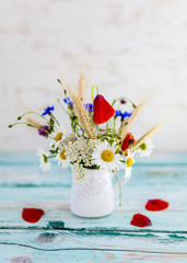 Wildflowers in a jug on a wooden table.