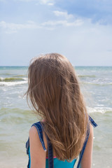 Fototapeta na wymiar Young girl with long blond hair on the sea coast