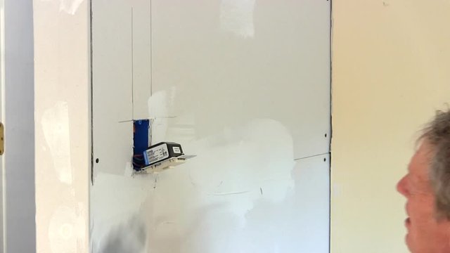 Man Applies Joint Compound To Drywall Seam Before Applying Drywall Tape.