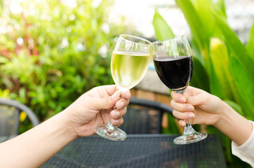 Two people clinking each other's glasses with wine on green background