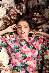 Woman lying on flowers in studio photo. Beauty and fashion. Cosmetics and skincare