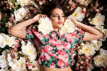 Woman lying on flowers in studio photo. Beauty and fashion. Cosmetics and skincare